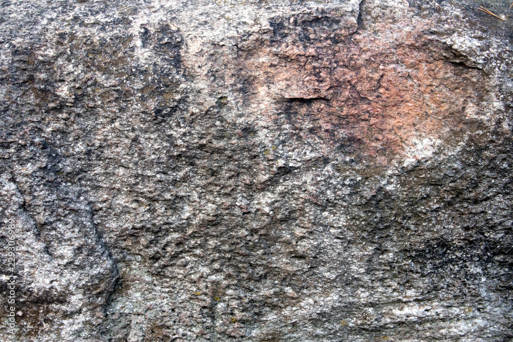 Uneven surface of big grey granite boulder with pink inclusion, may be used as background or texture Uneven surface of big grey granite boulder with pink inclusion, may be used as background or texture