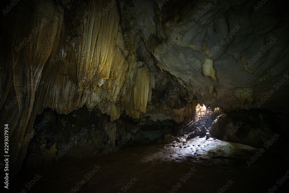 Stalactites, stalagmites and mouth at the dark Tham Loup Cave near Vang Vieng, Vientiane Province, Laos.