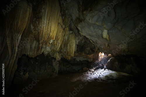 Stalactites, stalagmites and mouth at the dark Tham Loup Cave near Vang Vieng, Vientiane Province, Laos.
