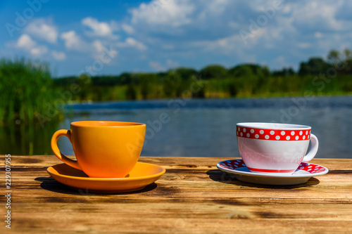 Two cups of coffee on wooden table at the riverside