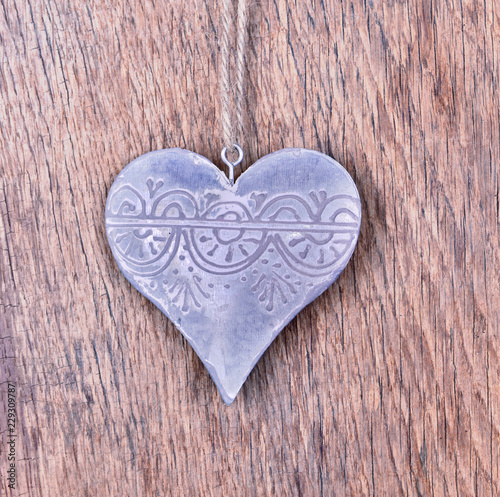 steel shaped heart hanging by a string on wooden background