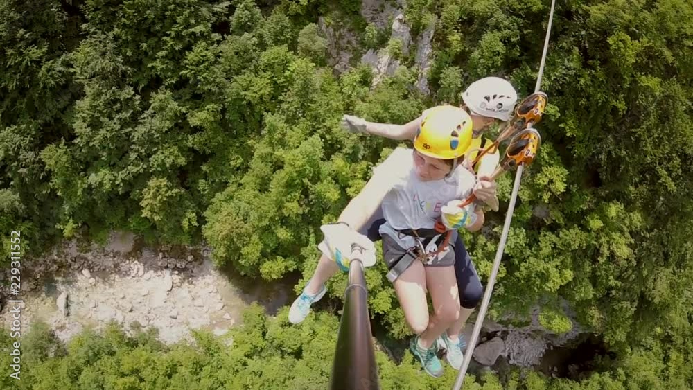Two people in tandem canopying over the forest on zipline in Slovenia.