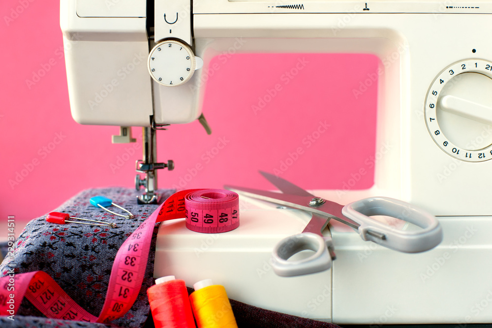Sewing machine and cloth on a pink background. Sew clothes on a