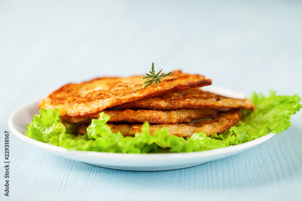 Potato pancakes with salad on a blue background. Selective focus. Rösti . Swiss national dish. Potato pancakes with salad on a blue background. Selective focus. Rösti . Swiss national dish.