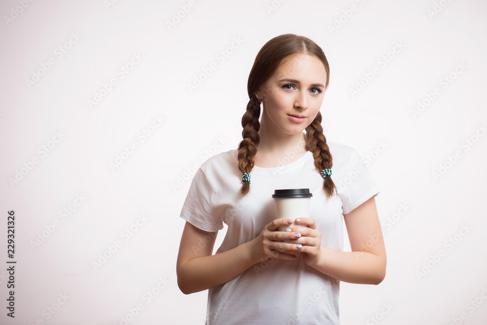 Portrait of attractive cute student girl with pigtails and wearing white shirt holding coffee cup Portrait of attractive cute student girl with pigtails and wearing white shirt holding coffee cup