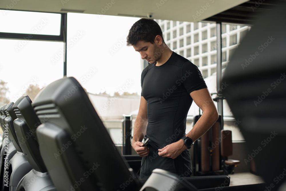 young man preparing to run on treadmill young man preparing to run on treadmill