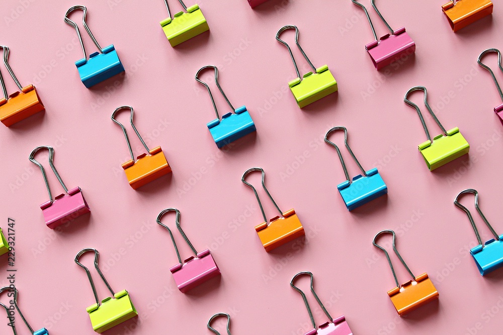 Business, office supplies, teamwork, corporation, collaboration or unity concept : Lines of multi colored binder clips on pink background - obrazy, fototapety, plakaty 