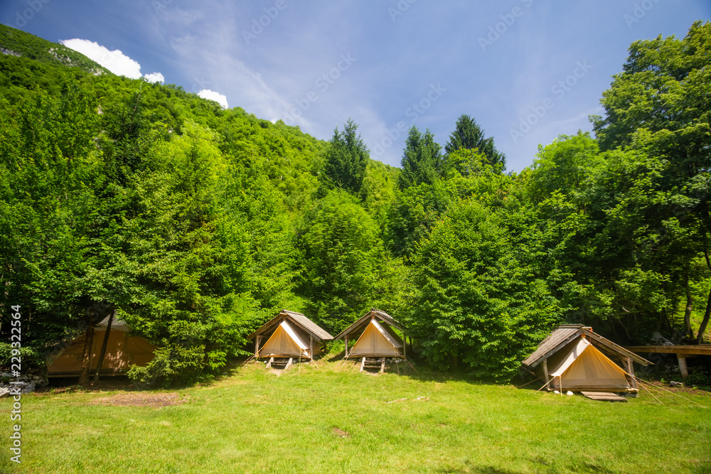 Cute fabric tents protected by wooden huts in alpine environment, Slovenia.