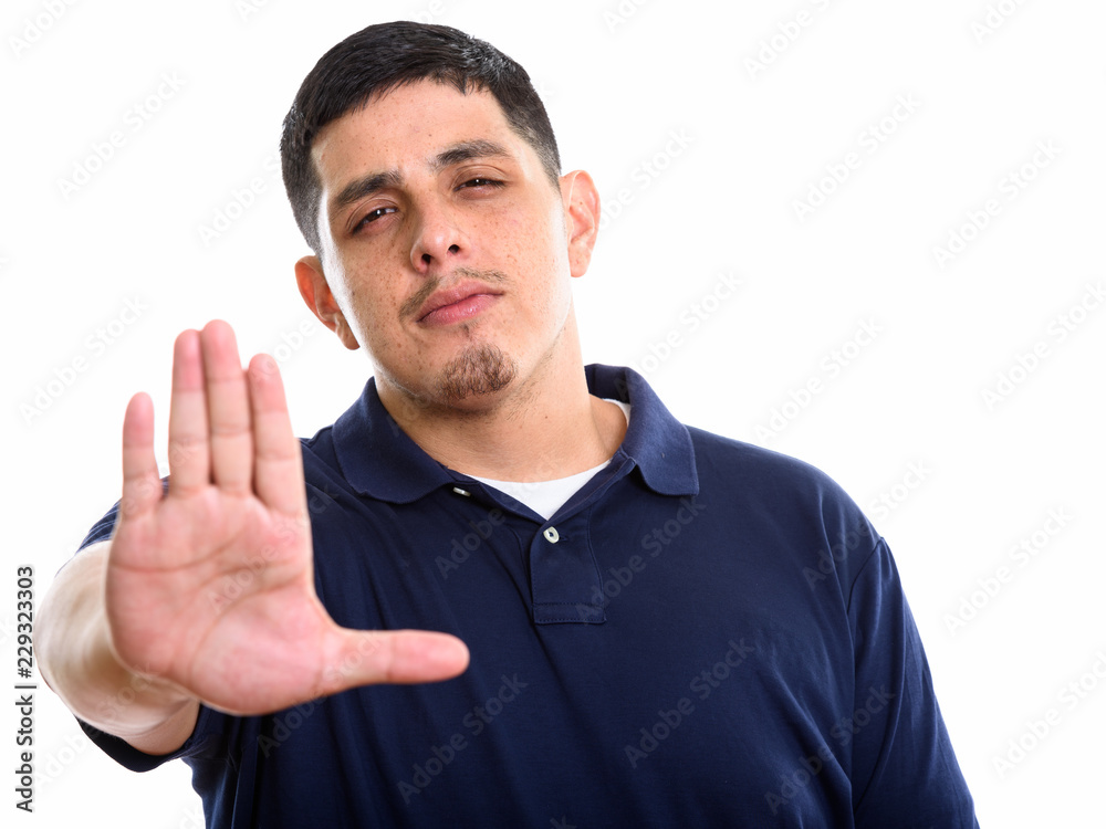 Studio shot of young Hispanic man with stop hand gesture Studio shot of young Hispanic man with stop hand gesture