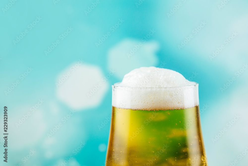 Goblet style beer glass on dark natural wooden table with light blue bokeh background. Goblet style beer glass on dark natural wooden table with light blue bokeh background.
