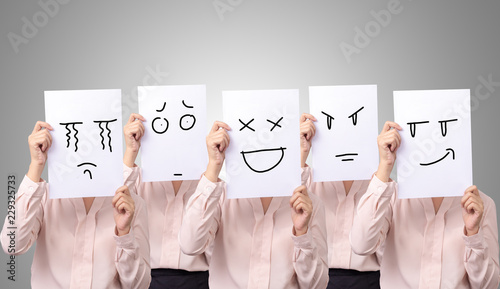 five businesswoman holding a card with drawing facial expressions different emotion feelings face on white paper