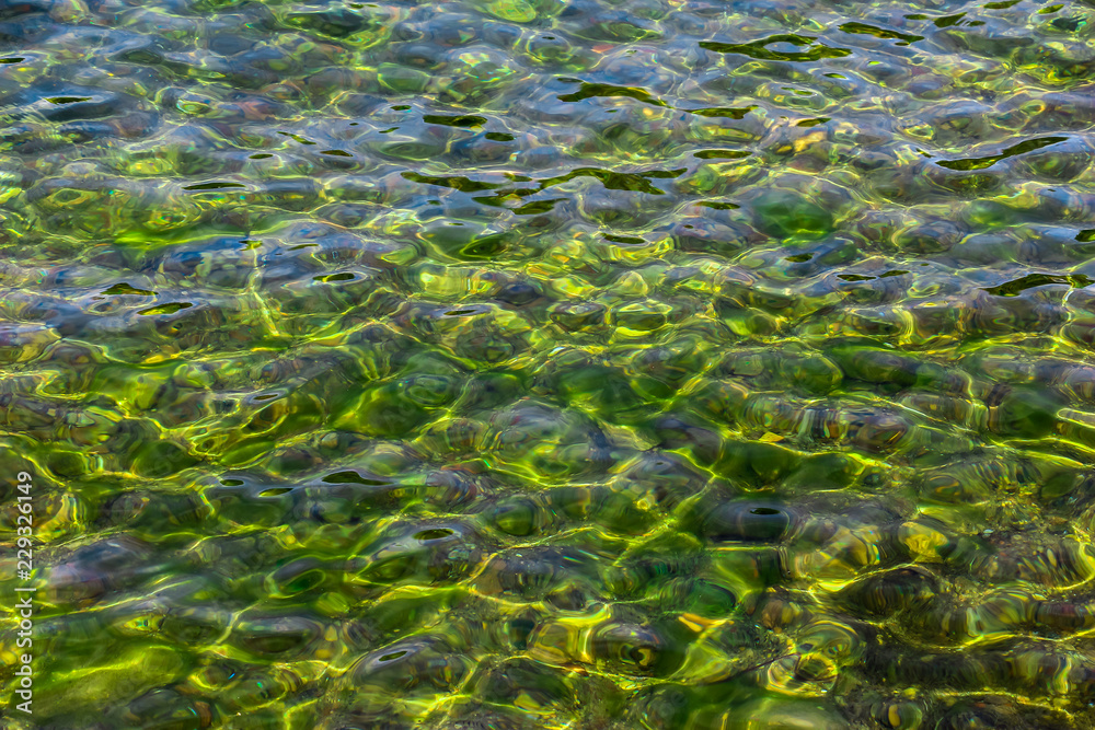 Surface of transparent, clear, beautiful colorfull water. Reflection and refraction of light in water. Abstract natural sea water background.