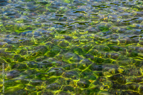 Surface of transparent, clear, beautiful colorfull water. Reflection and refraction of light in water. Abstract natural sea water background.