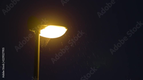 Rainy night and a solitary lamppost. Midsize view of raindrops against a lamppost bright light. photo