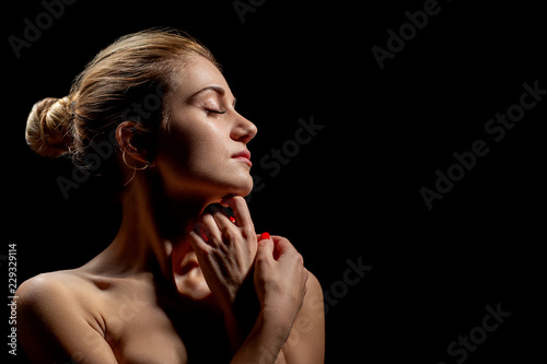 beautiful female profile with bare shoulders on black background with copy space
