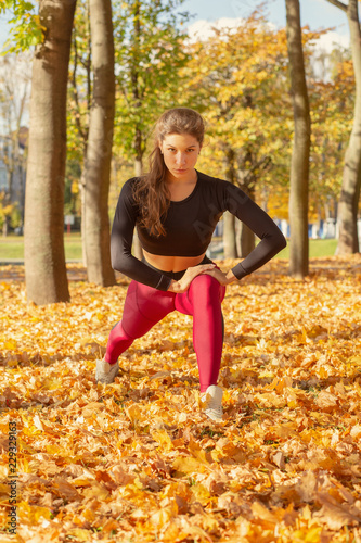 slim sporty woman stretching in autumn city park