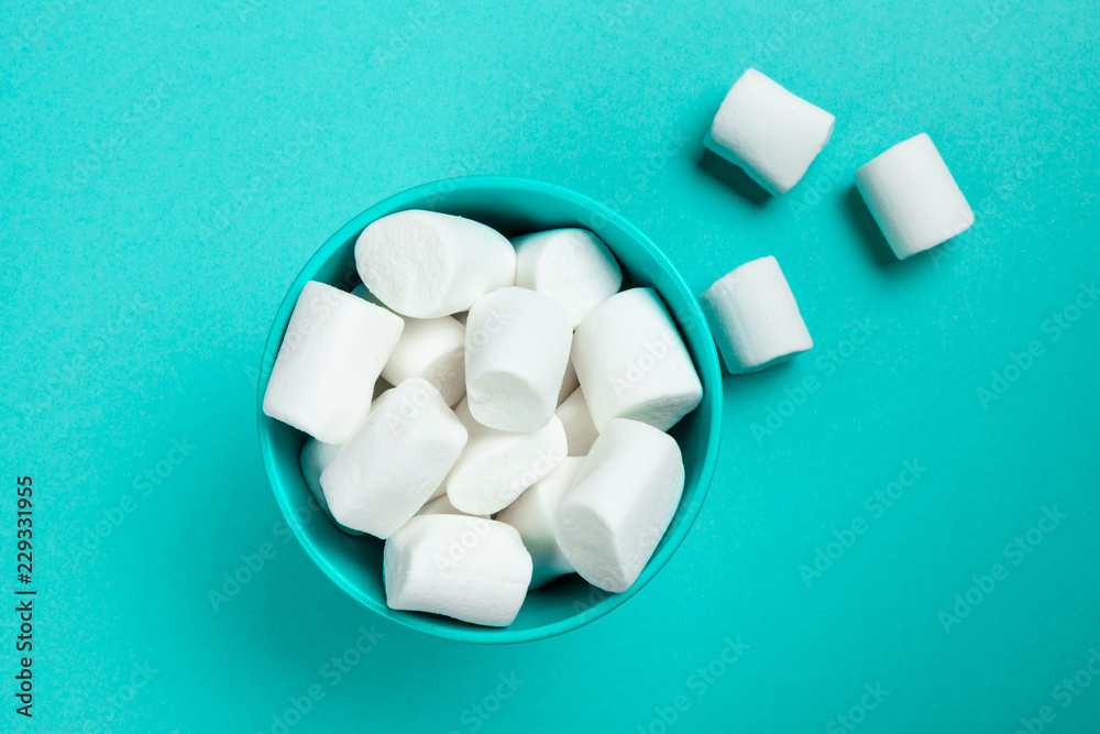 marshmallow laid out on blue paper background. pastel creative textured pattern. marshmallow laid out on blue paper background. pastel creative textured pattern.