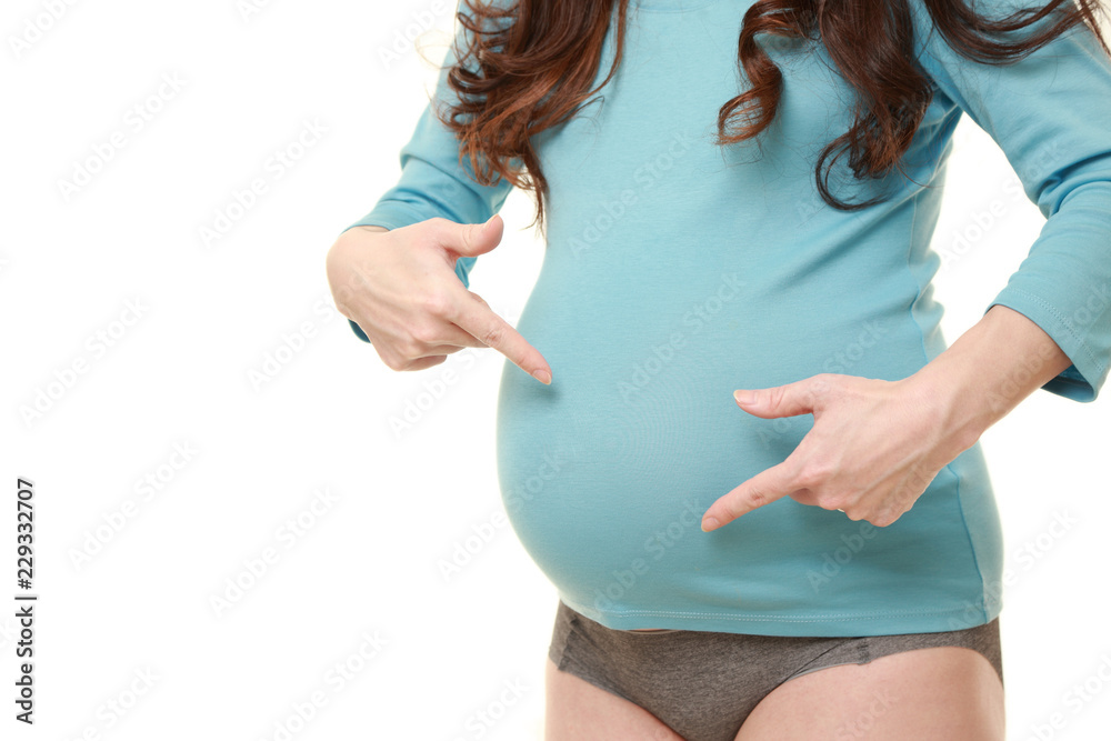 自分のお腹を指差して妊娠していることをアピールする水色のシャツを着た臨月の妊婦 Stock Foto Adobe Stock