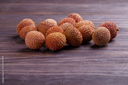 Fresh ripe lychees scattered on a wooden table.