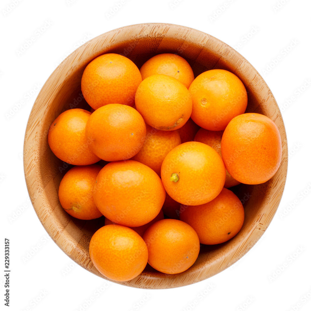 Fresh whole kumquats in wooden bowl isolated on white background. Top view. Fresh whole kumquats in wooden bowl isolated on white background. Top view.