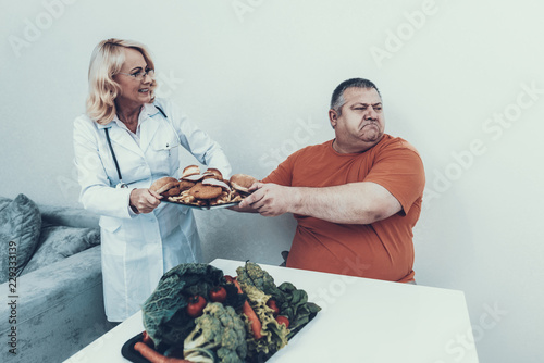 Doctor in White Coat Offers Vegetables to Fat Man. photo