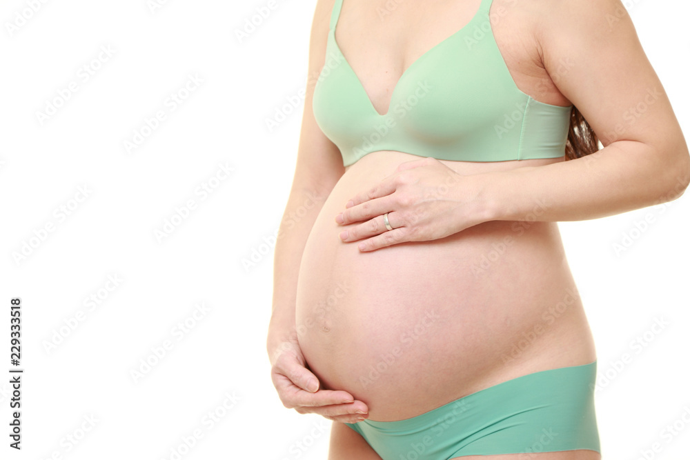 お腹を労わる緑色の下着を着た臨月の妊婦