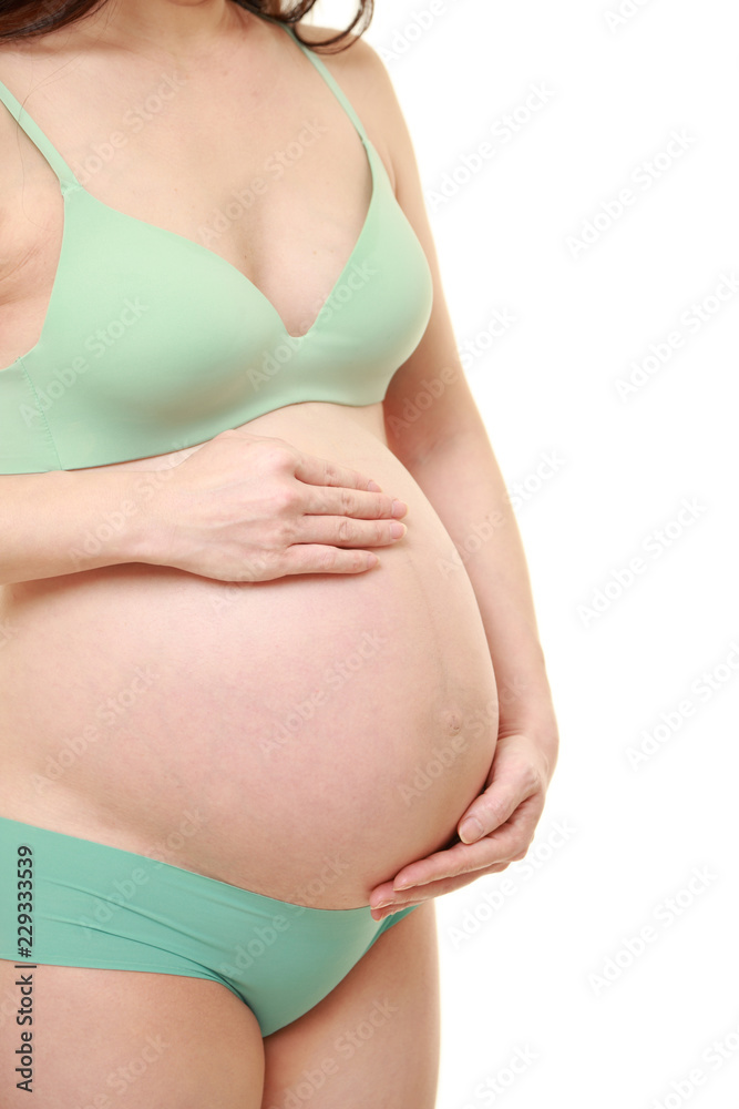 お腹を労わる緑色の下着を着た臨月の妊婦 お腹を労わる緑色の下着を着た臨月の妊婦