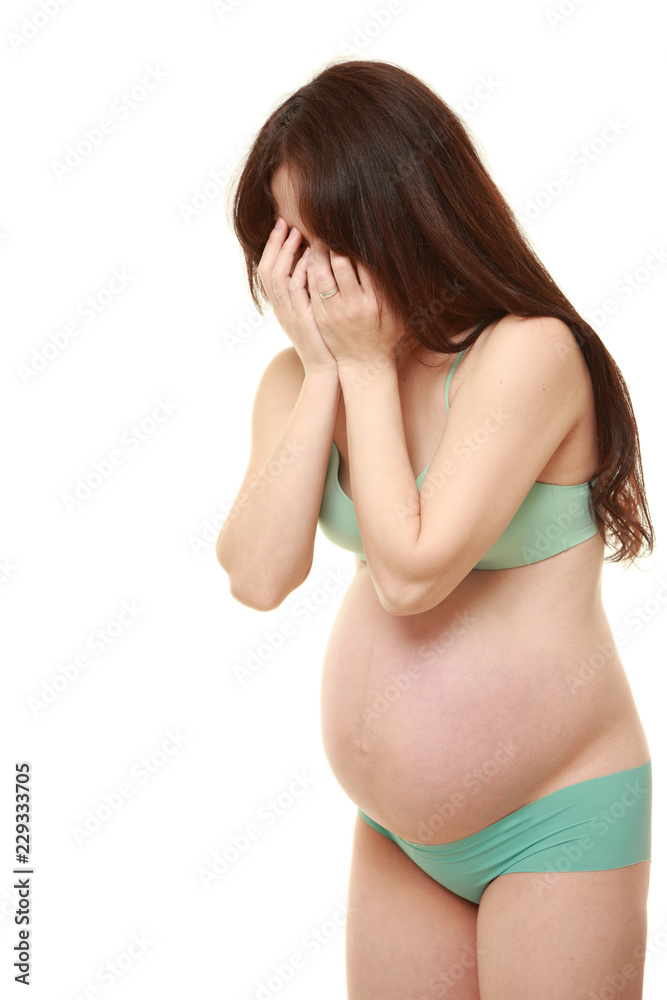 Obraz premium 両手で顔を覆う緑色の下着を着た臨月の妊婦