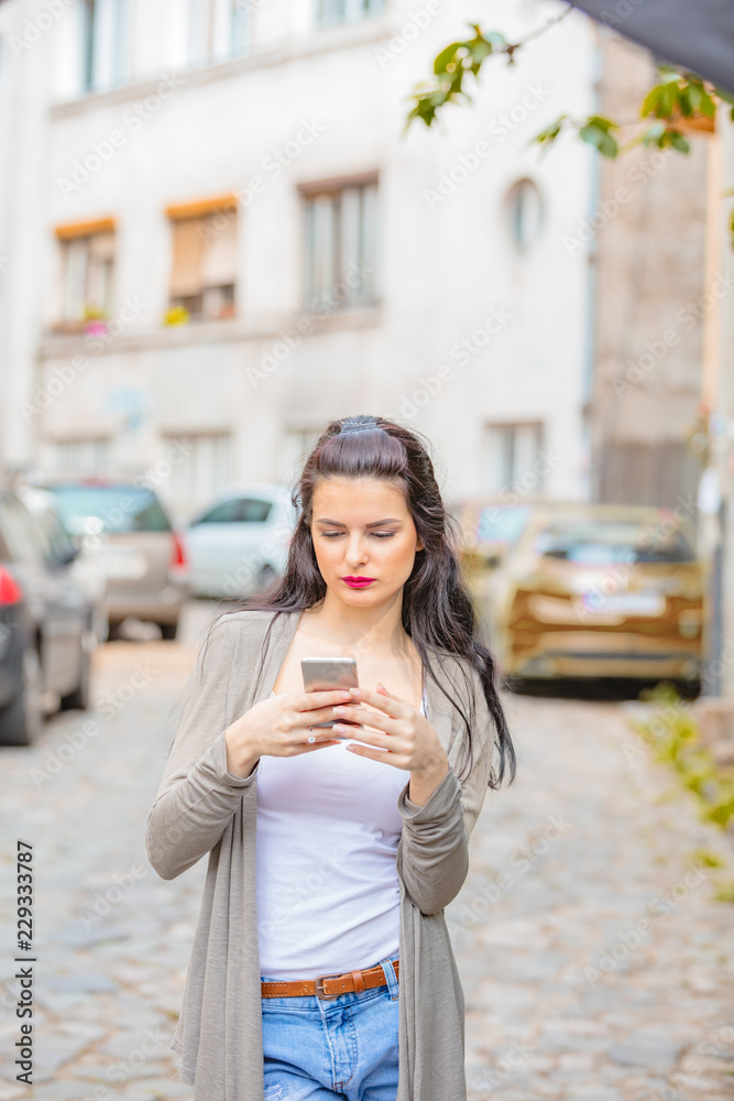 Cute young woman using cellphone in urban surroundings. Cute young woman using cellphone in urban surroundings.