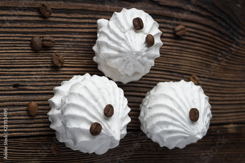 Sweet dessert - vanilla marshmallow (zephyr) on a wooden table with coffee beans, selective focus.