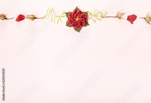 Autumn composition made of crocheted rose flowers and dry leaves on pastel pink background. Mother's, Valentines, Women's, Wedding Day concept. Autumn, fall concept. Flat lay, top view, copy space