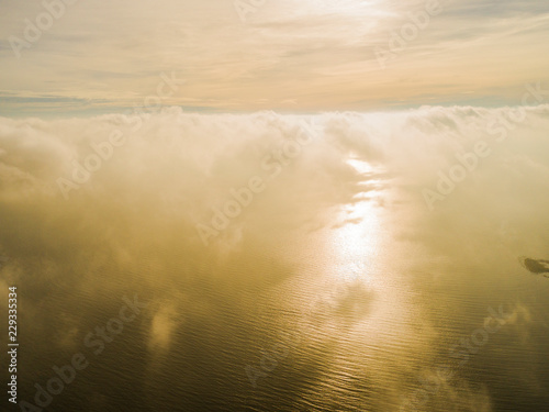 Aerial view White clouds in blue sky. Top view. View from drone. Aerial bird's eye view. Aerial top view cloudscape. Texture of clouds. View from above. Sunrise over the sea