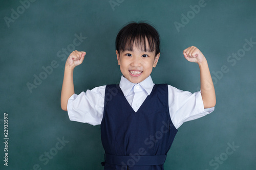Asian Chinese little girl in uniform standing with arms up