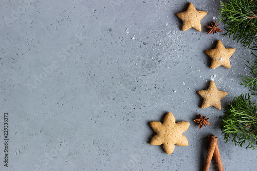 Traditional Christmas gingerbread cookies and juniper branch with Christmas decor on grey concrete background. Copy space for text.