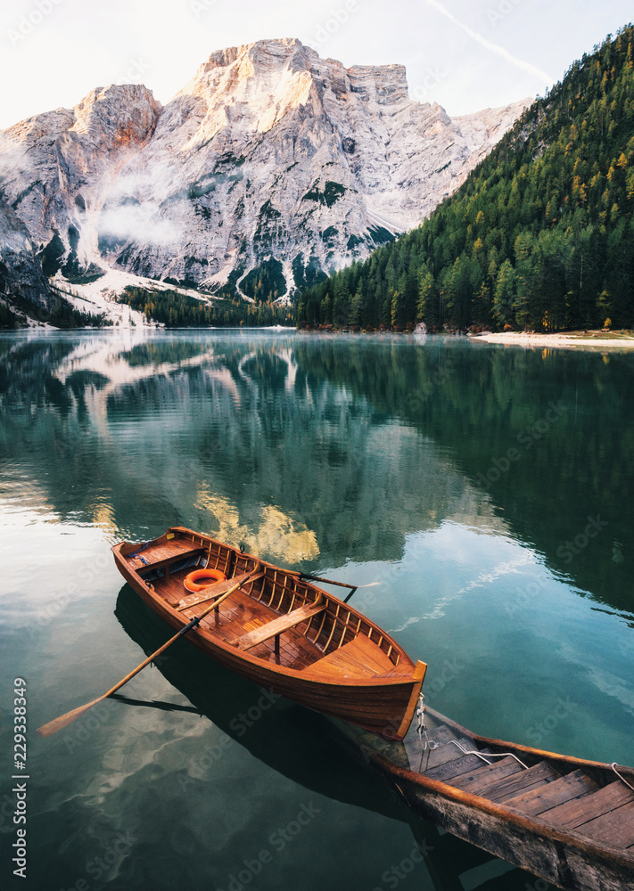 Boats and slip construction in Braies lake with crystal water in background of Seekofel mountain in Dolomites in morning, Italy Pragser Wildsee