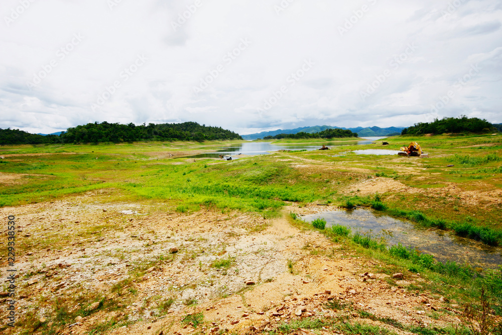 Landscape of Green Moss and meadow grass growing on cracked clay land near the lake in forest mountain at Thailand