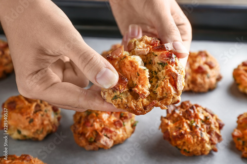 Woman holding tasty sausage ball over baking tray, closeup
