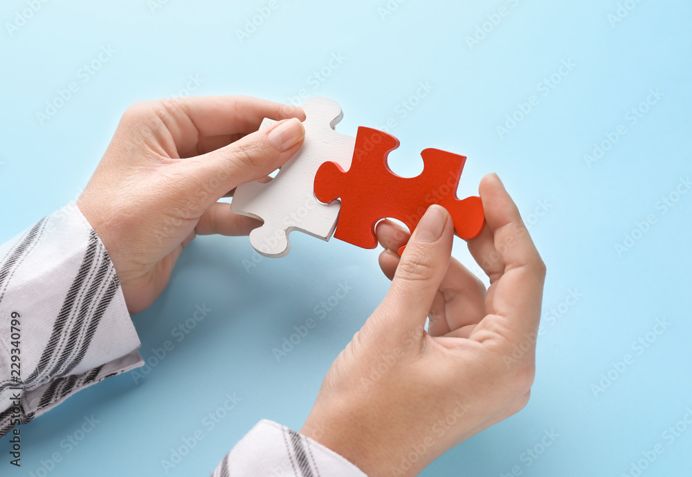 Female hands with pieces of puzzle on color background Female hands with pieces of puzzle on color background