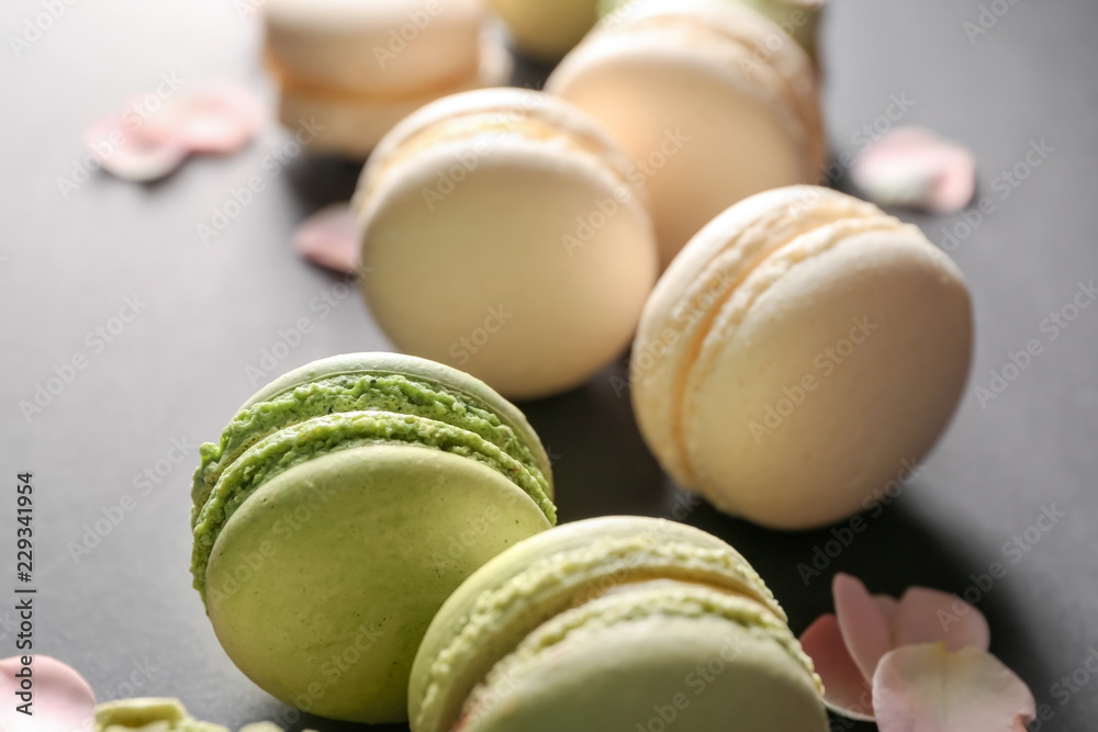 Fresh tasty macaroons with rose petals on grey table Fresh tasty macaroons with rose petals on grey table