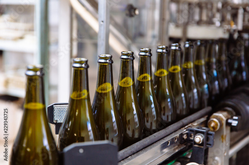 Billede på lærred Glass bottles on the automatic conveyor line at the champagne or wine factory