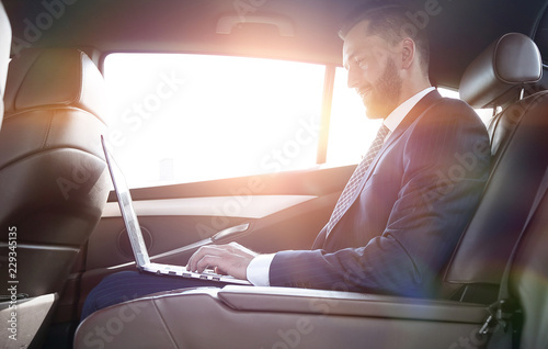 confident businessman sitting on the backseat of a prestigious car © ASDF