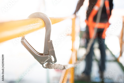 Industrial Worker with safety protective equipment loop hanging on the bar besides