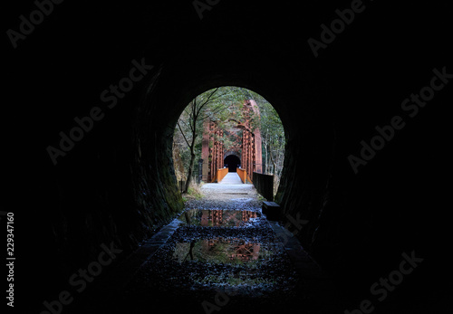 Dark black tunnel leads to abandoned railway bridge photo