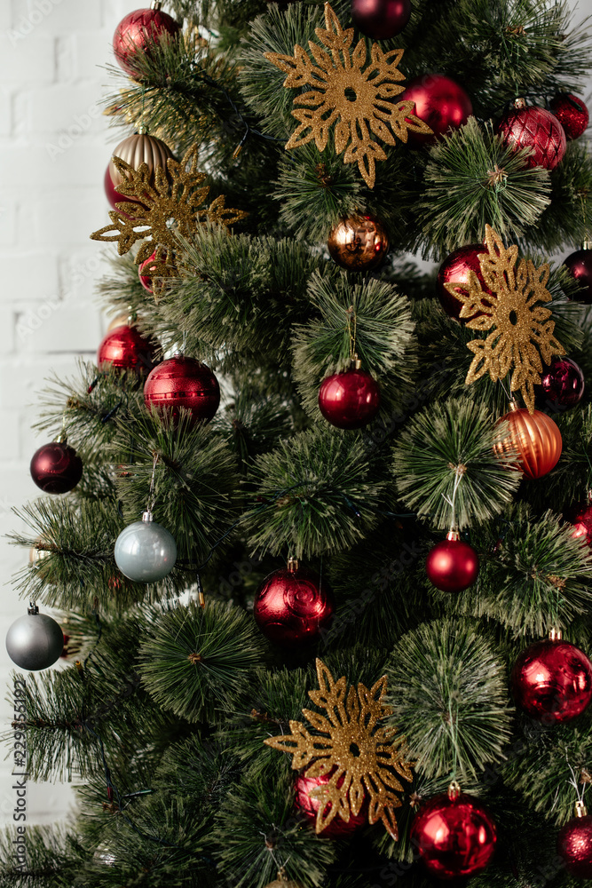 christmas tree with baubles and golden snowflakes in room