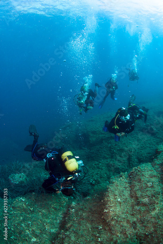Scuba divers underwater in the deep blue sea.