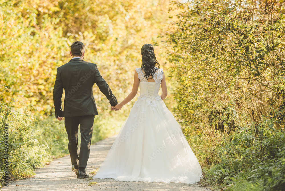 Wedding autumn. Happy bride and groom walking in the autumn forest