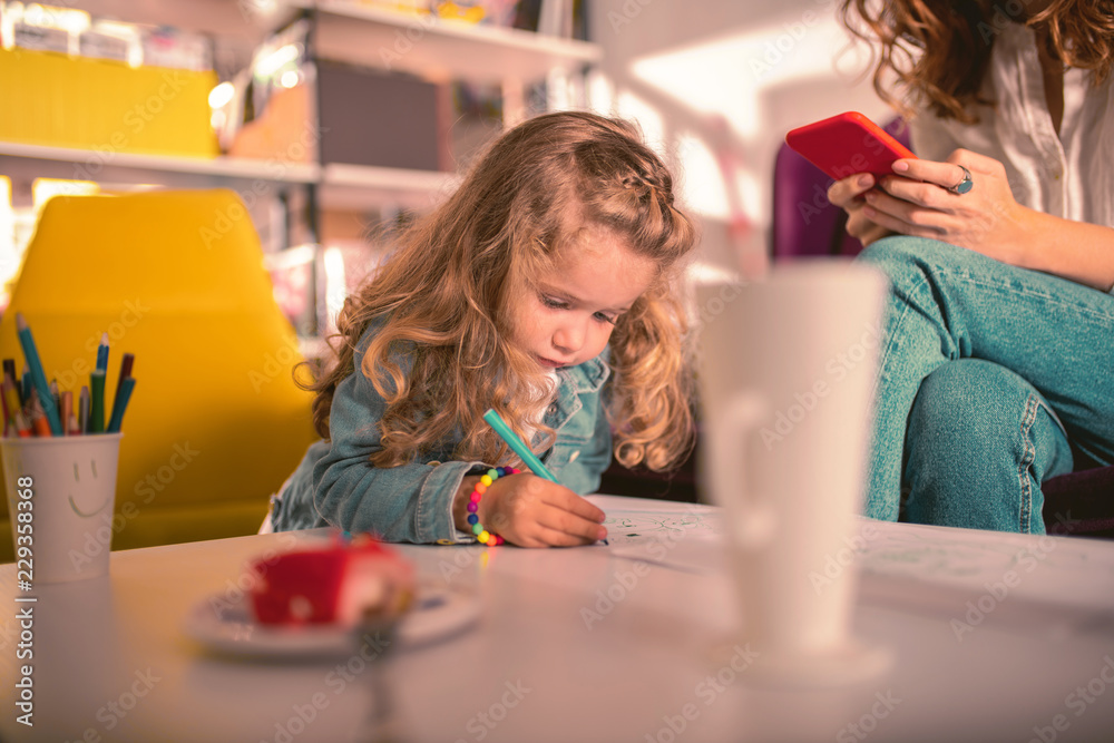 So bored. Charming blonde child bowing head while looking at her picture So bored. Charming blonde child bowing head while looking at her picture