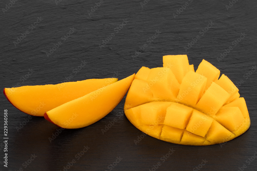ripe mango cut in half and diced on dark slate ripe mango cut in half and diced on dark slate