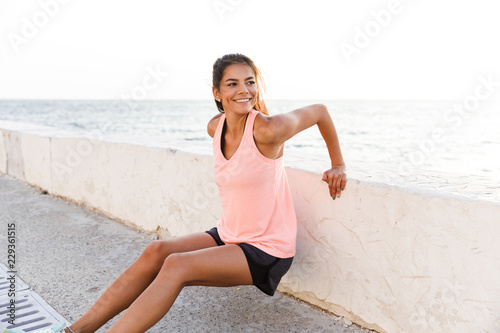Smiling young sportswoman warming up outdoors
