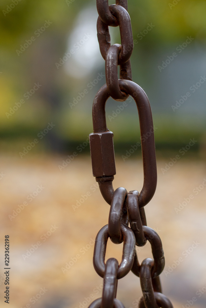 Old metal carbine for linking chain links. The steel carbine connects several chains into a single whole. The structure of the metal bracket, chain links and carbine on the blur background. Old metal carbine for linking chain links. The steel carbine connects several chains into a single whole. The structure of the metal bracket, chain links and carbine on the blur background.